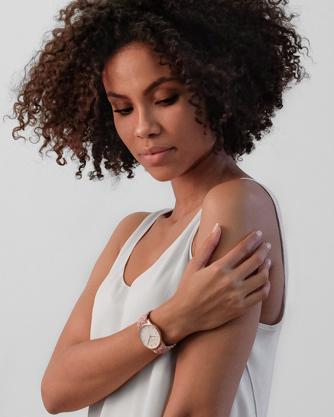 Smiling young woman wearing a Tweed Co. watch with pink braided strap on an urban background