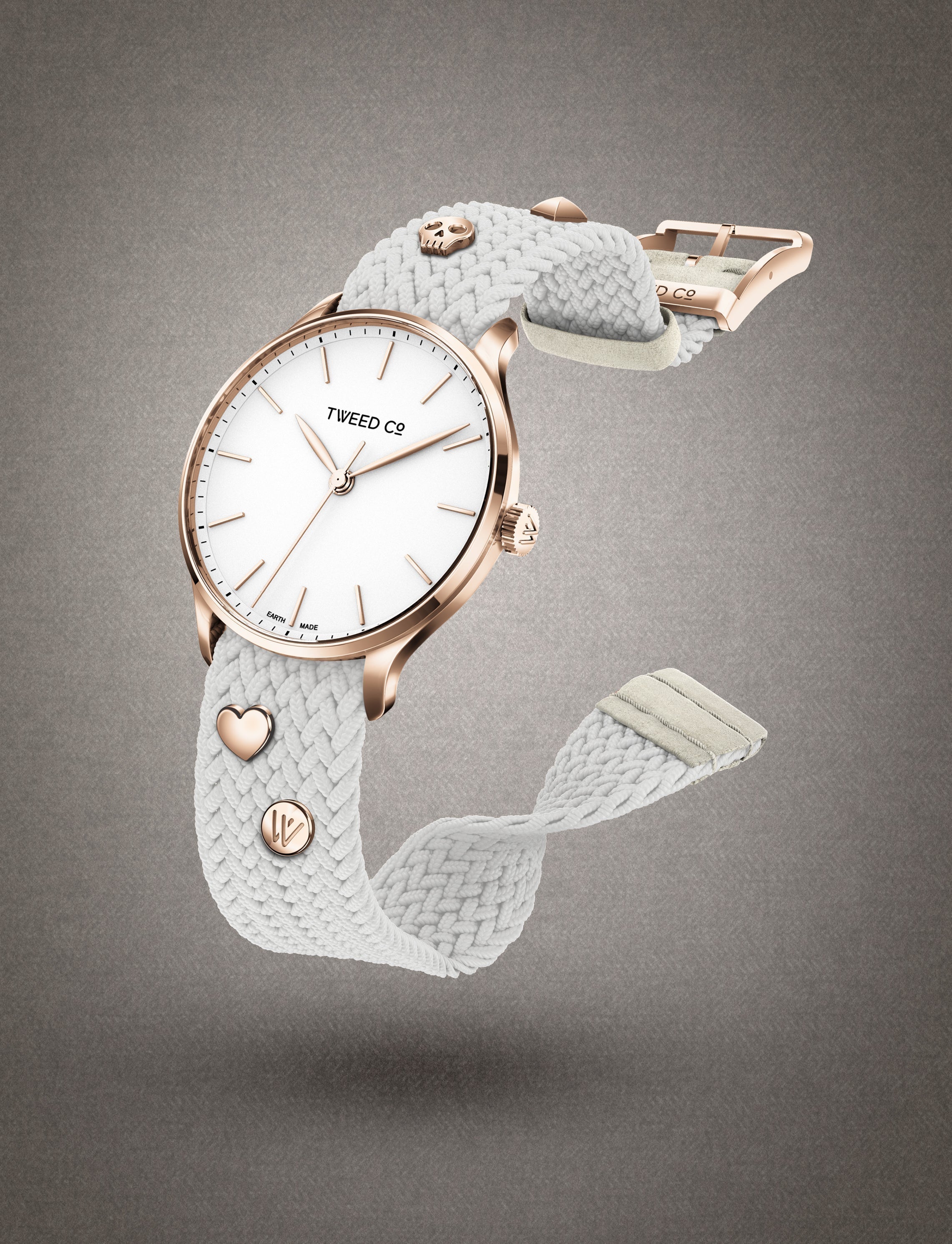 Kate Uhr mit weißem Zifferblatt, die am Handgelenk getragen wird, mit elegantem weißem geflochtenem Armband und schlichten Details - ein Symbol für Stil und Raffinesse, das von Tweed Co. signiert wurde.
